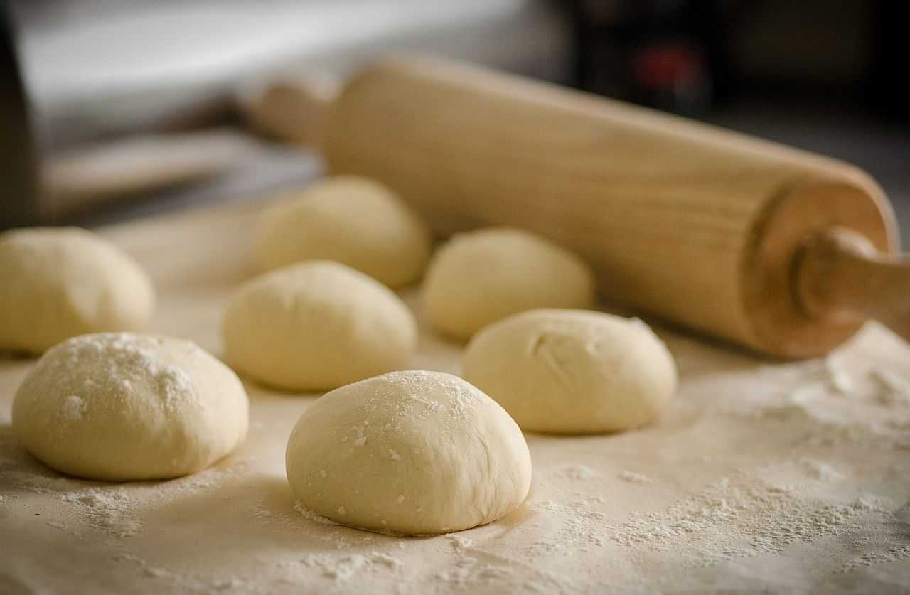 Balls of pizza dough with rolling pin
